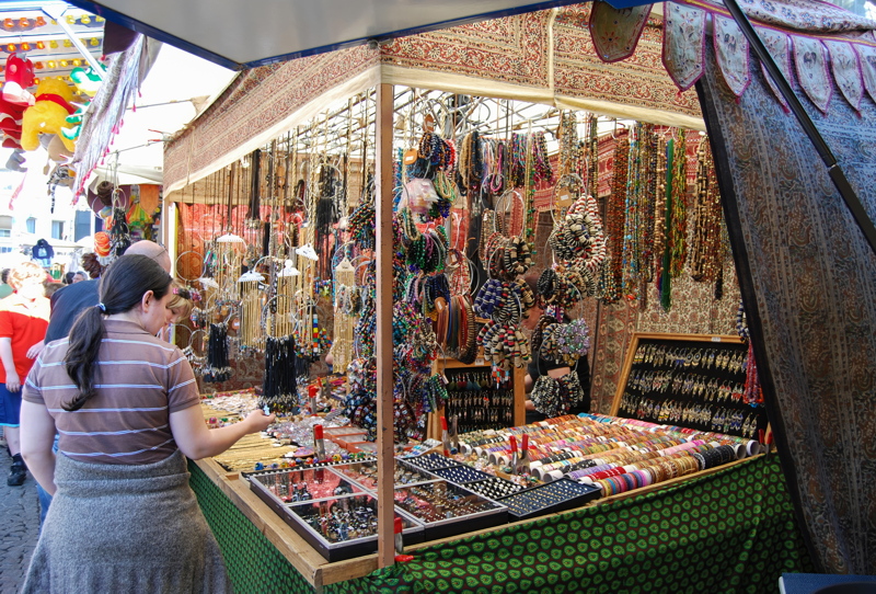 15 - Stall densely packed with a wide array of handmade fashion accessories, including colorful necklaces, bracelets, and silver jewelry featuring precious gems